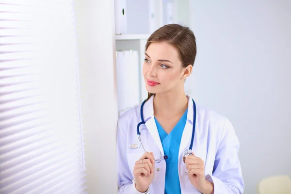 Woman doctor is standing near window with crossed arms,isolated — Stock Photo, Image