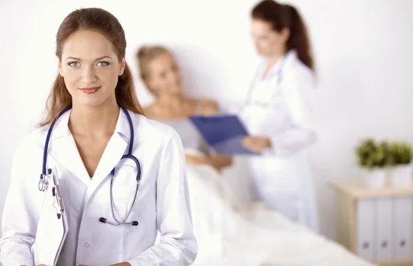 Médico sonriente con una carpeta en uniforme de pie en el hospital — Foto de Stock