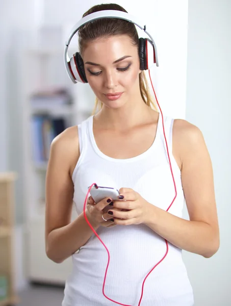 Mujer con auriculares escuchando música de pie en casa — Foto de Stock