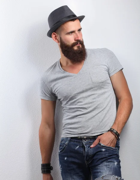 Portrait of handsome bearded man in hat standing , isolated on grey background — Stock Photo, Image