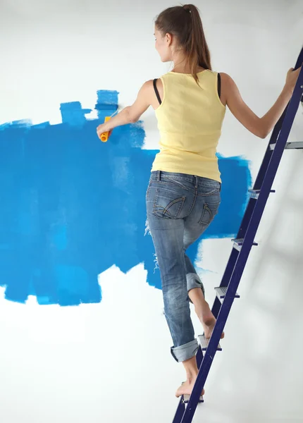 Glücklich schöne junge Frau beim Wandbemalen, neben Leiter stehend — Stockfoto