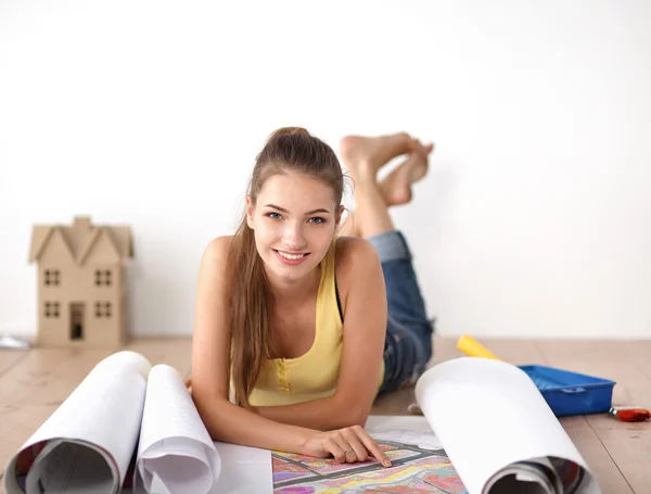 Jonge vrouw op de vloer liggen en kijken naar blauwdruk van nieuwe huis — Stockfoto