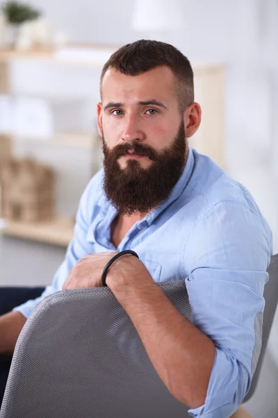 Jonge zakenman zit op stoel in functie — Stockfoto