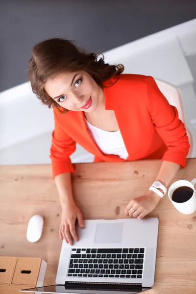 Mulher atraente sentada na mesa no escritório, trabalhando com computador portátil — Fotografia de Stock