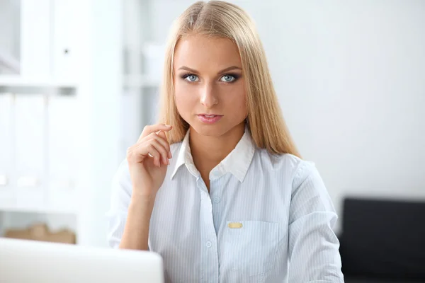 Atractiva mujer de negocios sentada en un escritorio con portátil en la oficina — Foto de Stock