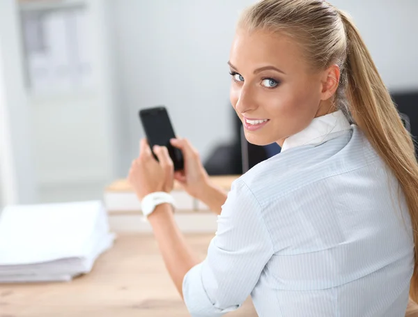Zakenvrouw stuurt bericht met smartphone zittend op kantoor — Stockfoto