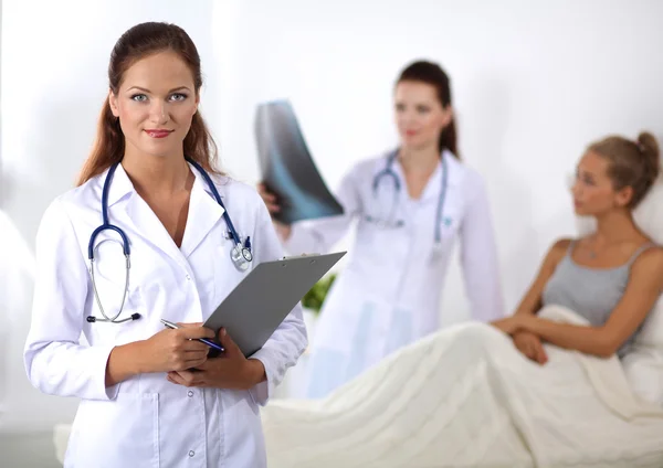 Médico sonriente con una carpeta en uniforme de pie en el hospital — Foto de Stock