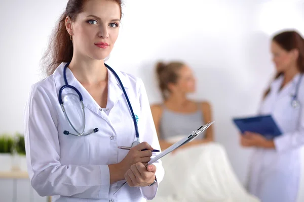 Sorridente medico donna con una cartella in uniforme in piedi in ospedale — Foto Stock