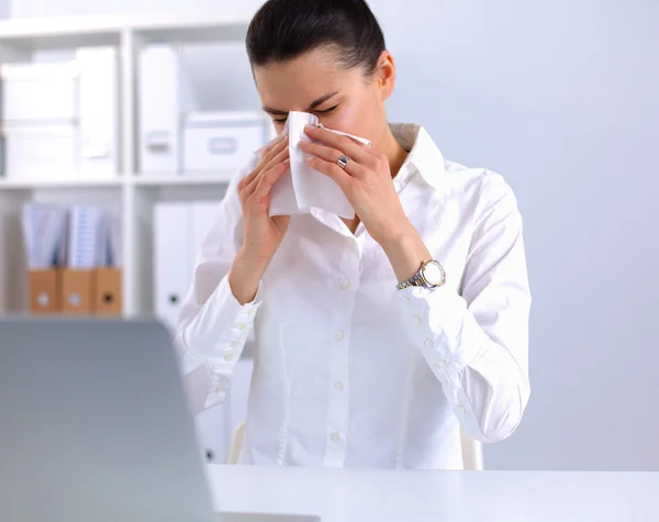 Junge Geschäftsfrau pustet sich die Nase, sitzt am Schreibtisch — Stockfoto