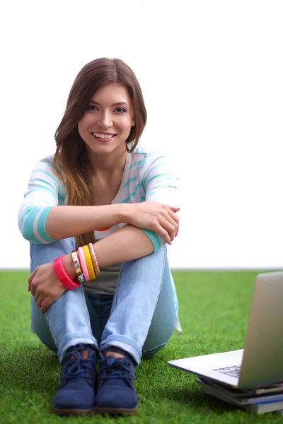 Ung kvinna med bärbar dator sitter på grönt gräs — Stockfoto