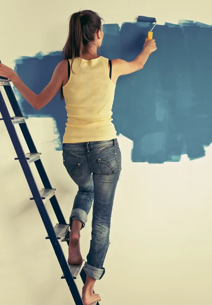 快乐美丽的年轻女子做墙画，正站在梯子上 — 图库照片