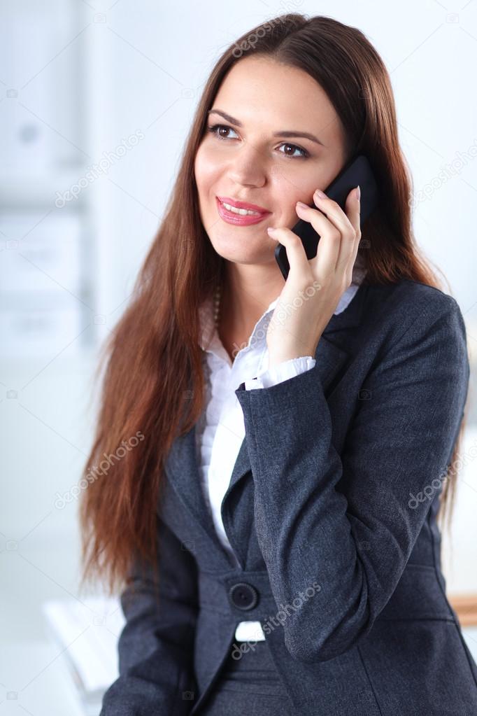 Smiling businesswoman talking on phone sitting at the office
