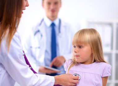 Kadın doktor ameliyatta steteskopla çocuğu muayene ediyor.