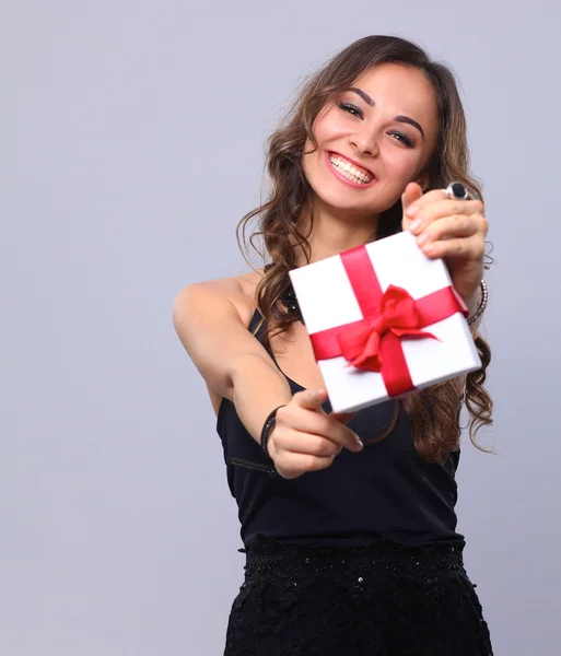 Молода жінка щаслива посмішка тримає подарункову коробку в руках, ізольовано на сірому фоні — стокове фото