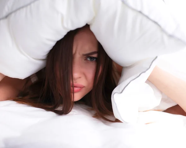 Mujer acostada en la cama y cerrando las orejas con almohada — Foto de Stock