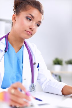 Kadın araştırmacı, beyaz arka planda izole edilmiş ilaç şişeleri ve mataralarla çevrili.