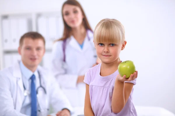 Kind en geneeskunde concept - vrouwelijke arts geeft een appel aan klein meisje — Stockfoto