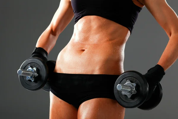 Athletic woman pumping up muscules with dumbbells — Stock Photo, Image