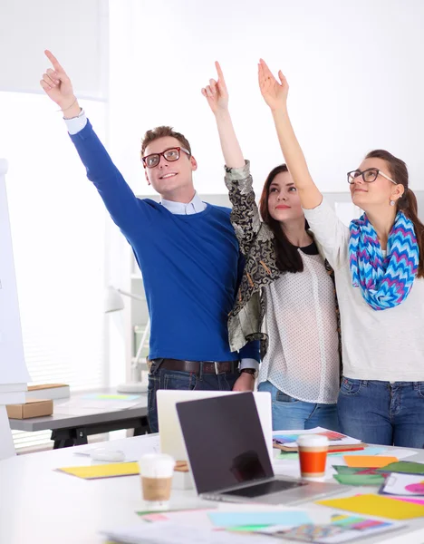 Unga företagare står på kontor nära skrivbord och pekar uppåt — Stockfoto
