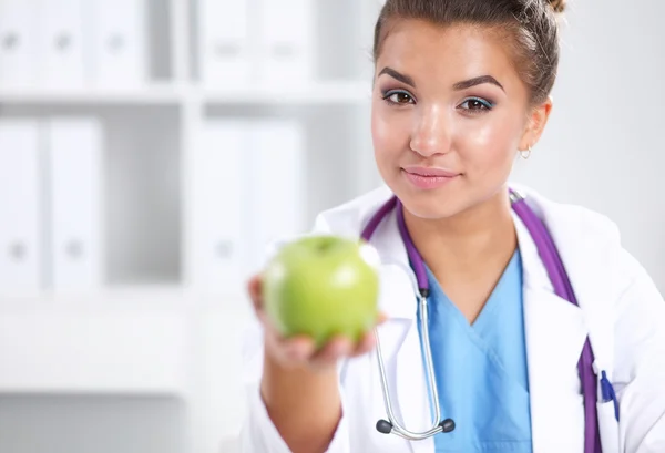 Kvinnliga läkare hand som håller ett grönt äpple, stående — Stockfoto