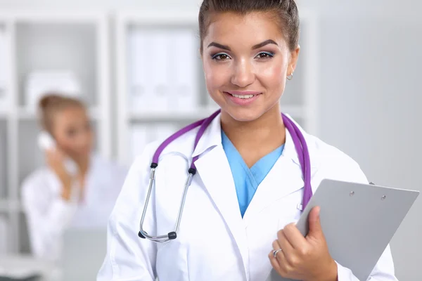 Lächelnde Ärztin mit Ordner in Uniform steht im Krankenhaus — Stockfoto