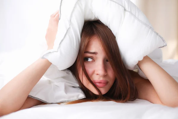 Mulher deitada na cama e fechando as orelhas com travesseiro — Fotografia de Stock