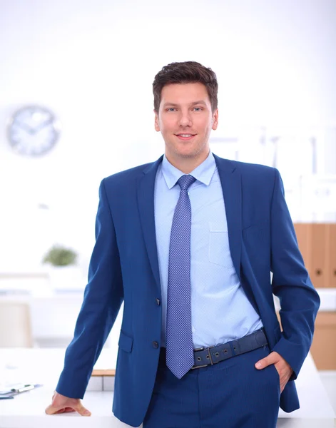 Business man or manager standing against his desk at the office — Stock Photo, Image