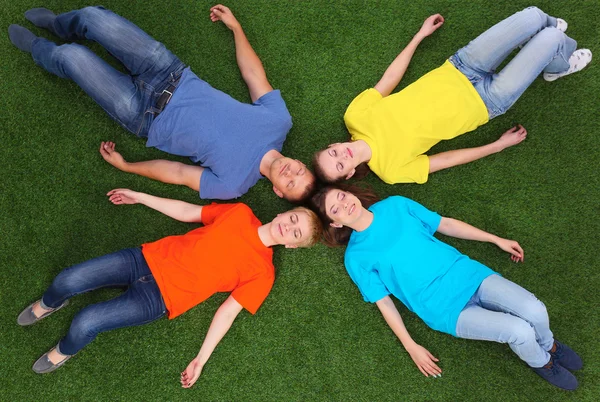 Group of young people lying on green grass Royalty Free Stock Images