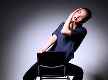 Genç bir kadın sandalyede oturuyor.