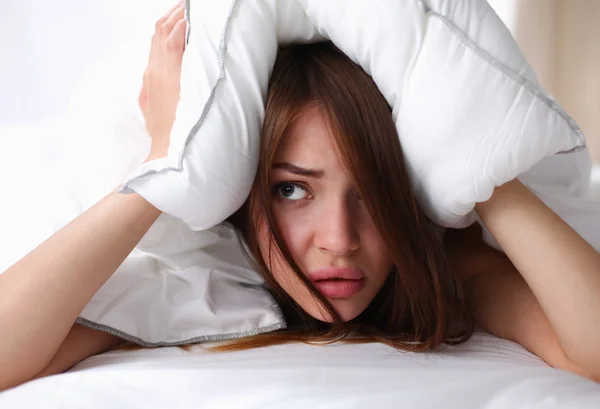 Mujer acostada en la cama y cerrando las orejas con almohada — Foto de Stock