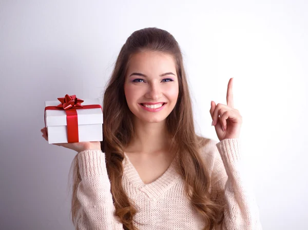 Ung kvinna lyckligt leende hålla presentförpackning i händer, står över grå bakgrund — Stockfoto