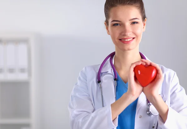 Mladá žena doktor drží červené srdce, stojící — Stock fotografie