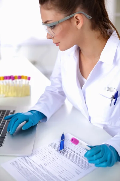 Woman researcher is surrounded by medical vials and flasks, isolated on white background — Stock Photo, Image