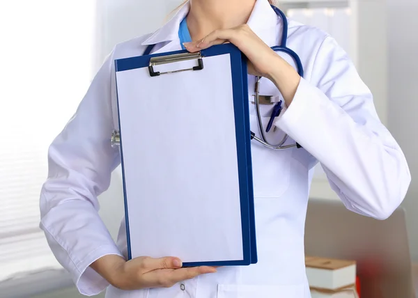 Médico sonriente con una carpeta en uniforme de pie — Foto de Stock