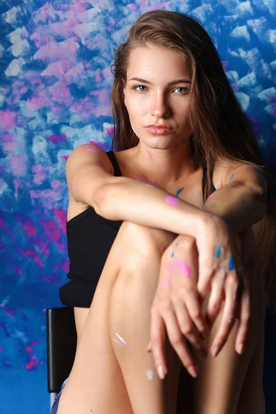 Young woman sitting near painting wall — Stock Photo, Image