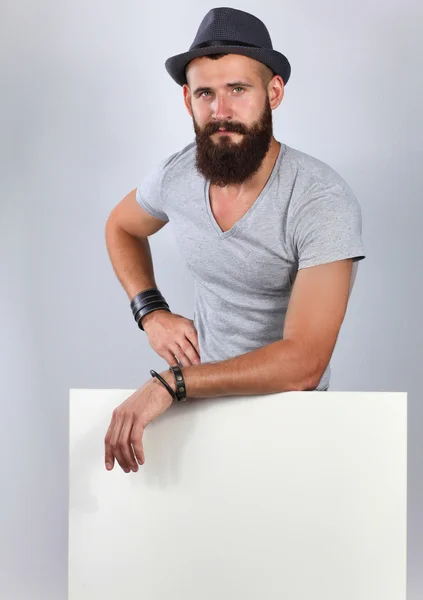 Portrait of young man in hat standing near blank, isolated on white background — Stock Photo, Image