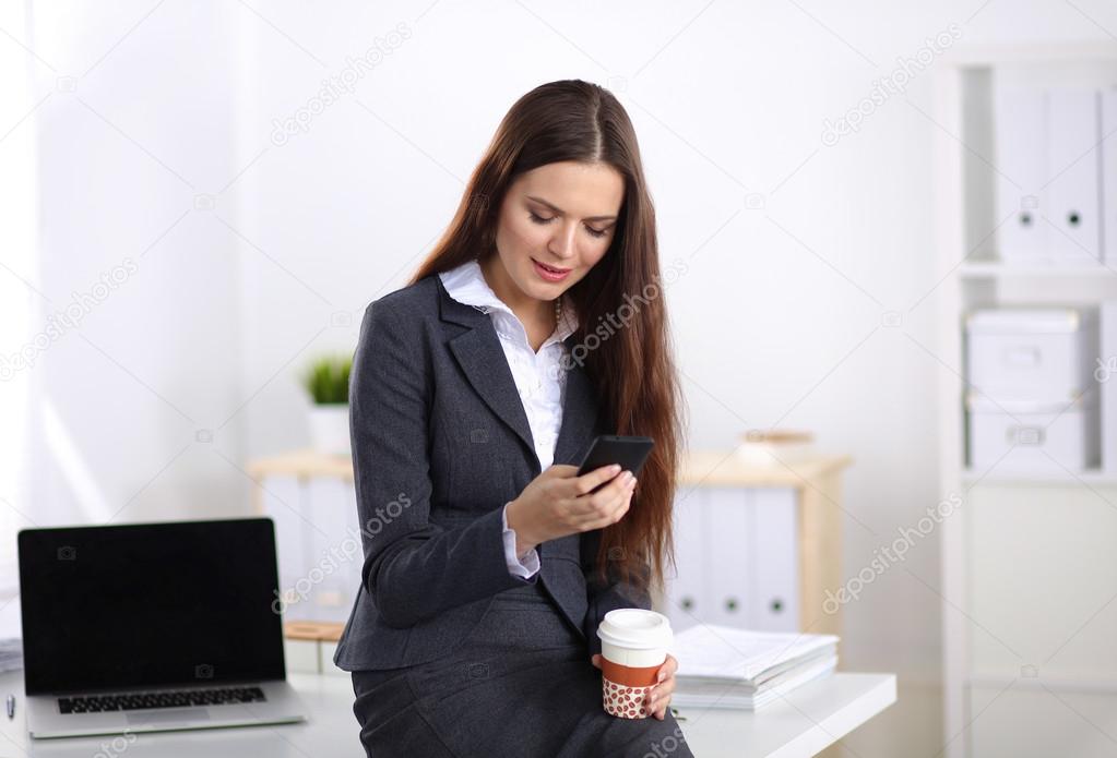 Businesswoman sending message with smartphone sitting