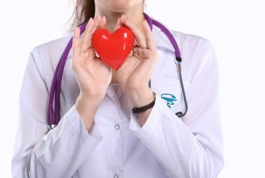 Kırmızı bir kalp taşıyan genç bir kadın doktor, beyaz arka planda izole edilmiş.