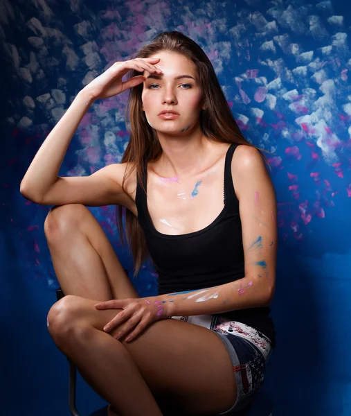 Young woman sitting near painting wall — Stock Photo, Image