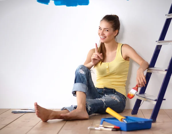 Portrait de peintre femme assise sur le sol près du mur après la peinture . — Photo