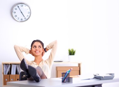 İş kadını ellerini başının arkasına koyup bir ofis sandalyesinde oturuyor.