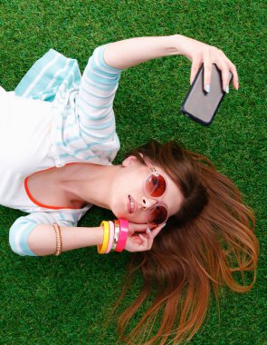 güzel ve genç birbayan yeşil çim yalan onu telefonla selfie yapma