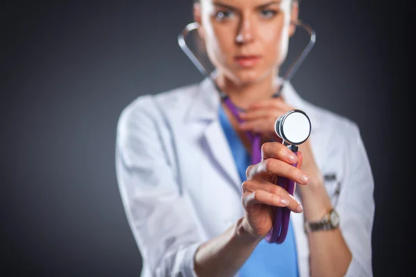 Женщина-врач со стетоскопом слушает, изолирована на сером фоне — стоковое фото