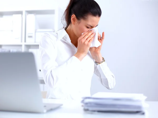 Junge Geschäftsfrau pustet sich die Nase, sitzt am Schreibtisch — Stockfoto