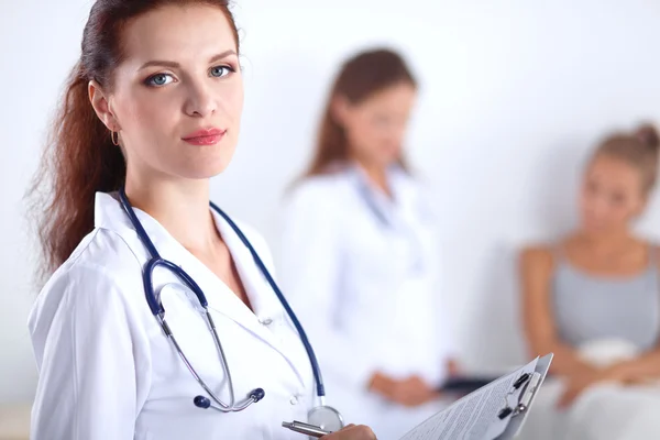 Médico sonriente con una carpeta en uniforme de pie en el hospital — Foto de Stock