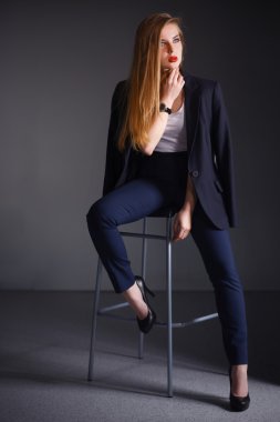 Genç bir kadın sandalyede oturuyor.