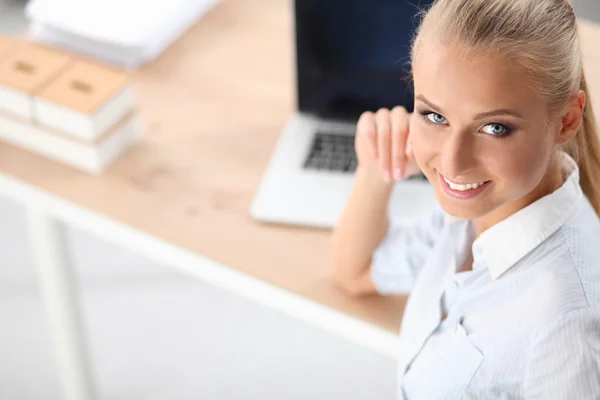 Aantrekkelijke zakenvrouw zit op een bureau met laptop in het kantoor — Stockfoto