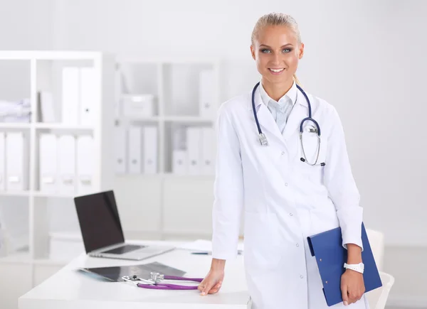 Lächelnde Ärztin mit Ordner in Uniform steht im Krankenhaus — Stockfoto