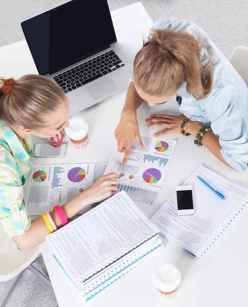 Två kvinnor arbetar tillsammans på kontoret, sitter på skrivbordet — Stockfoto