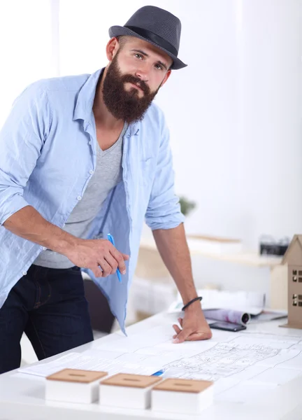 Portrait of male designer in hat with blueprints at desk — Stock Photo, Image